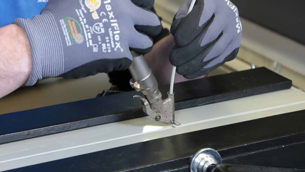 Soldadura manual de plásticos con aire caliente utilizando herramienta Leister, aplicando cordón de soldadura en plancha plástica