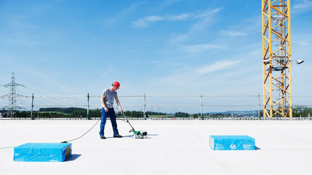 Instalador utilizando máquina automática Leister para soldadura de membranas TPO en techo plano