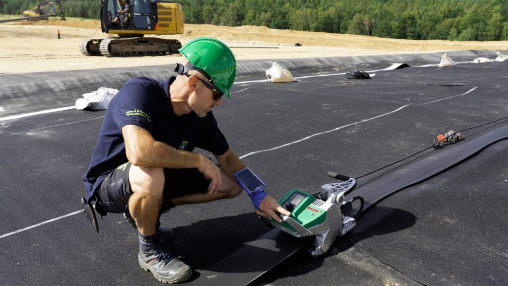 Técnico utilizando máquina automática Leister para soldar geomembranas PEAD en un aterro sanitario, garantizando impermeabilidad y seguridad ambiental