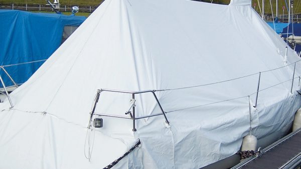 Barco cubierto con lona plástica blanca soldada, resguardado contra la intemperie en puerto