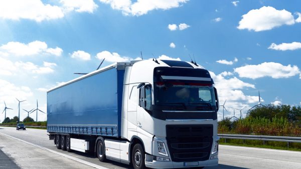 Camión tipo sider con lona lateral azul en carretera, utilizado para transporte seguro de cargas con cobertura plástica soldada