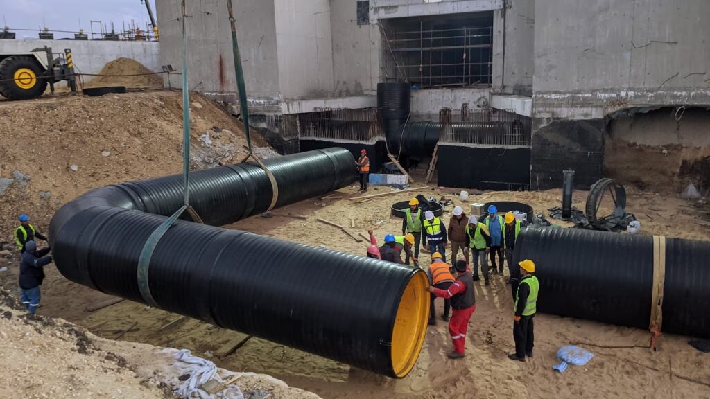 Obras de instalación de tuberías HDPE en la planta de tratamiento Bahr Al-Baqar en Egipto, con técnicos soldando tubos de gran diámetro en el sitio