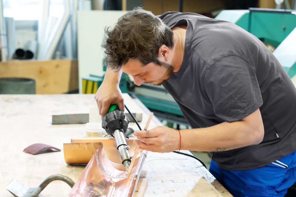 Profesional utilizando el kit de soldadura de hierro Leister TRIAC AT con punta de cincel para unir piezas metálicas con aire caliente en taller industrial