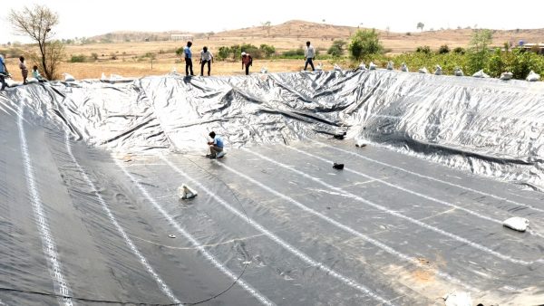 Instaladores indios preparan un reservorio agrícola recubierto con geomembranas soldadas con equipos Leister para evitar filtraciones de agua de lluvia