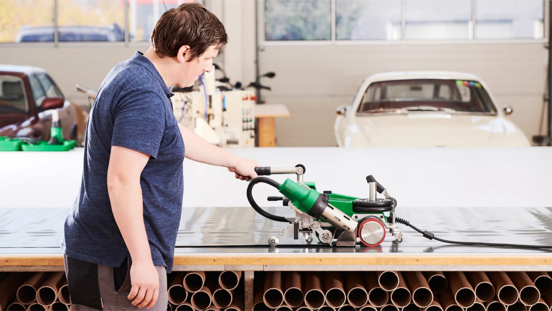 Operario utilizando la soldadora automática Leister UNIPLAN 500 para unir lonas sobre una mesa de trabajo