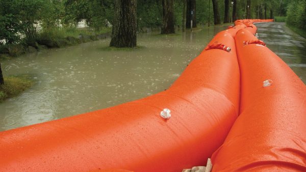 Barreras inflables de contención instaladas en caminos anegados para controlar el flujo de agua durante emergencias
