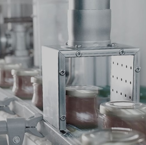 Línea de envasado automatizada donde los productos son esterilizados con aire caliente antes del sellado, asegurando higiene y conservación de los alimentos