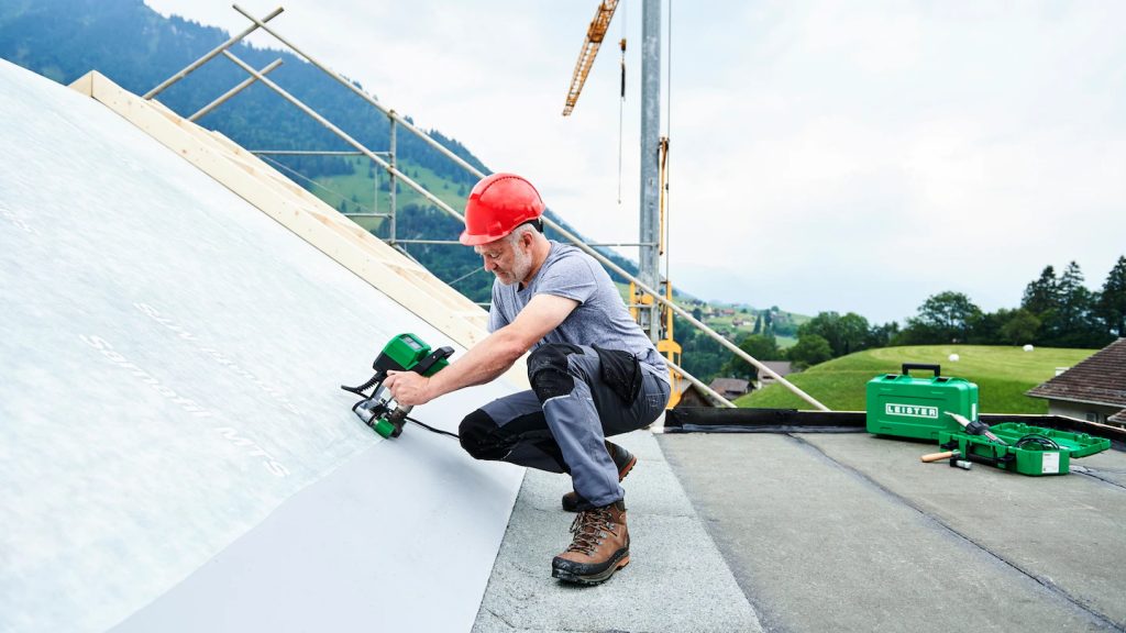 Obrero utilizando la máquina Leister UNIDRIVE 500 para soldar mantas de PVC en un techo inclinado