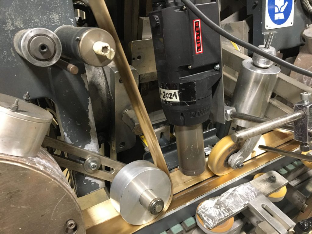 Soplador de aire caliente Leister MISTRAL 6 SYSTEM instalado en una máquina automatizada de ArcoDesign en Italia, utilizado para aplicar películas decorativas sobre marcos de madera con precisión térmica