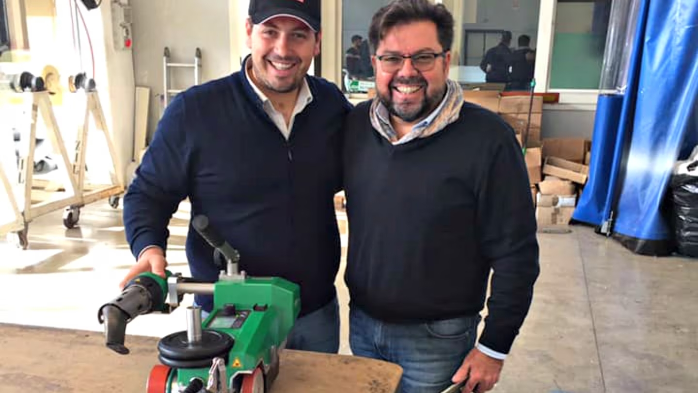 Equipo de Picariello Teloni junto a una soldadora automática Leister, reflejando la cooperación tecnológica para mejorar la producción de lonas de PVC
