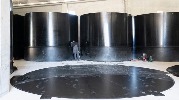 Grandes tanques de polietileno negro en las instalaciones de Basis 57, fabricados con extrusoras Leister WELDPLAST S2 para la cría sostenible de luciopercas en Suiza
