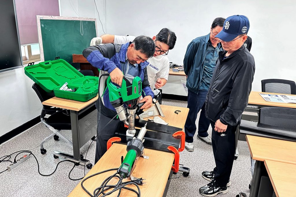 Técnicos coreanos realizando soldadura plástica de chapas de PEAD con extrusora Leister durante capacitación técnica