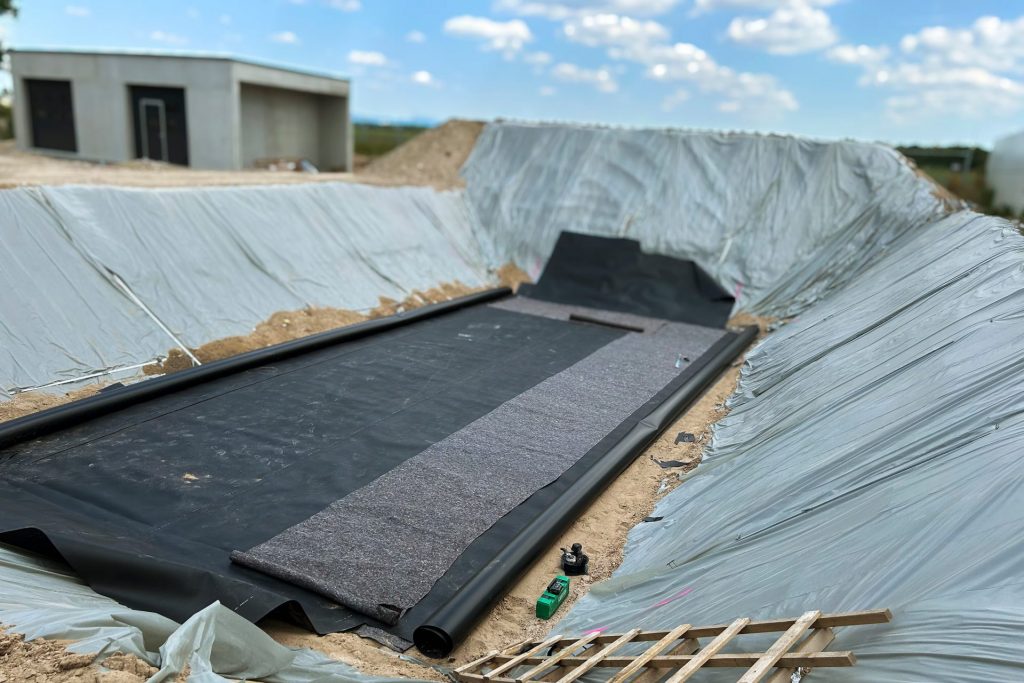 Reservatório em obra com geomembrana instalada e manta de proteção geotêxtil; impermeabilização para armazenamento de água com tecnologia Leister