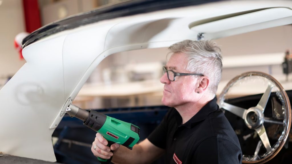 Operario usando la herramienta de aire caliente Leister SOLANO AT para acabado y ajuste de pieza plástica en la industria automotriz