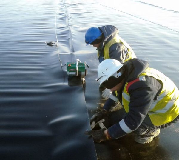Técnicos realizando soldadura por cuña caliente en geomembrana con equipo Leister para garantizar uniones de alta calidad