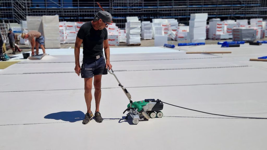 Operario utilizando la Leister VARIMAT 700 para soldar y sellar juntas de impermeabilización en un techo industrial, asegurando uniones uniformes y trazables