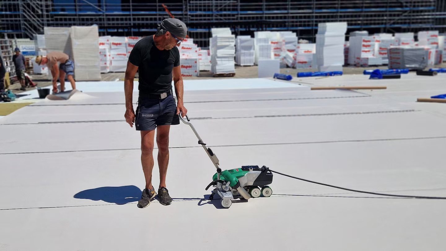 Operario utilizando la Leister VARIMAT 700 para soldar y sellar juntas de impermeabilización en un techo industrial, asegurando uniones uniformes y trazables