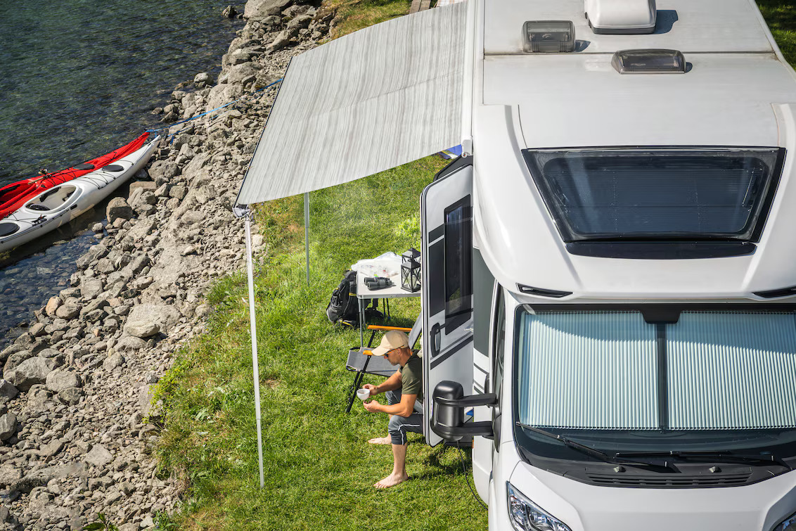 motorhome junto a la costa con toldo desplegado y zona de descanso exterior, aplicación de fabricación y mantenimiento de toldos con Leister
