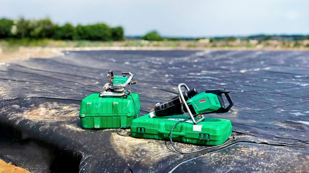 Equipos de soldadura de geomembranas Leister en obra de impermeabilización de lago en PEAD, con herramientas GEO listas para uniones estancas