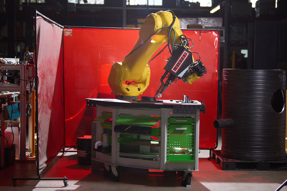 Celda de soldadura totalmente automatizada con robot FANUC y extrusora Leister WELDPLAST 200-i montados sobre mesa de trabajo industrial