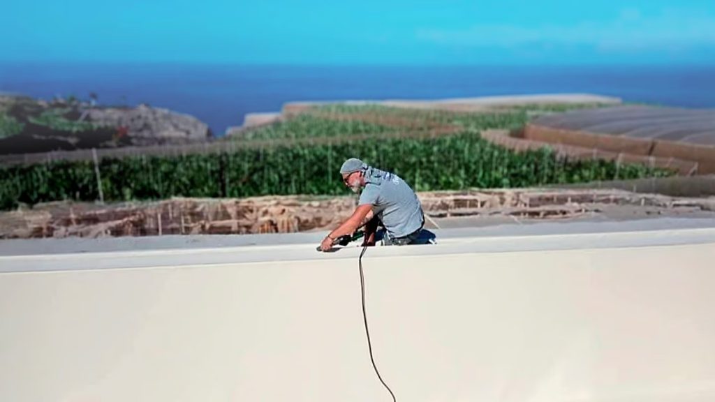 Profesional realizando una soldadura de detalle en la esquina de la membrana de la piscina utilizando la herramienta manual Leister TRIAC ST y un rodillo de presión