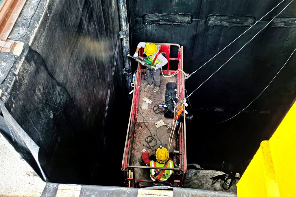 Interior del tanque de vertedero rígido, mostrando al técnico completando la impermeabilización con equipos de soldadura Leister.
