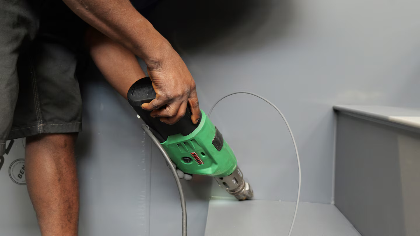 Técnico profesional utilizando la extrusora manual Leister FUSION 1 para la unión estanca de placas de polipropileno en la fabricación de la piscina