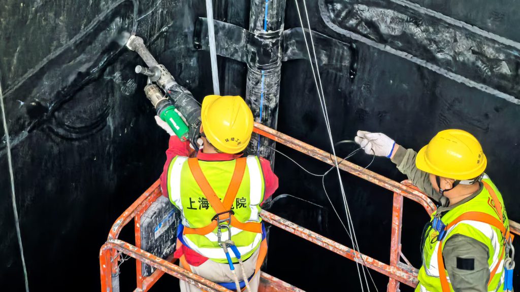 Operador especializado utilizando la extrusora manual Leister FUSION para realizar soldaduras de detalle y parches en la geomembrana del tanque de vertedero