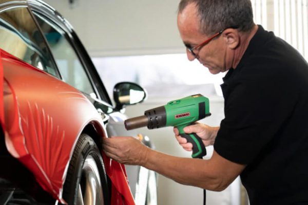 Proceso de ploteo completo en coche de carreras con diseño complejo, empleando tecnología de aire caliente Leister para la fijación precisa del material