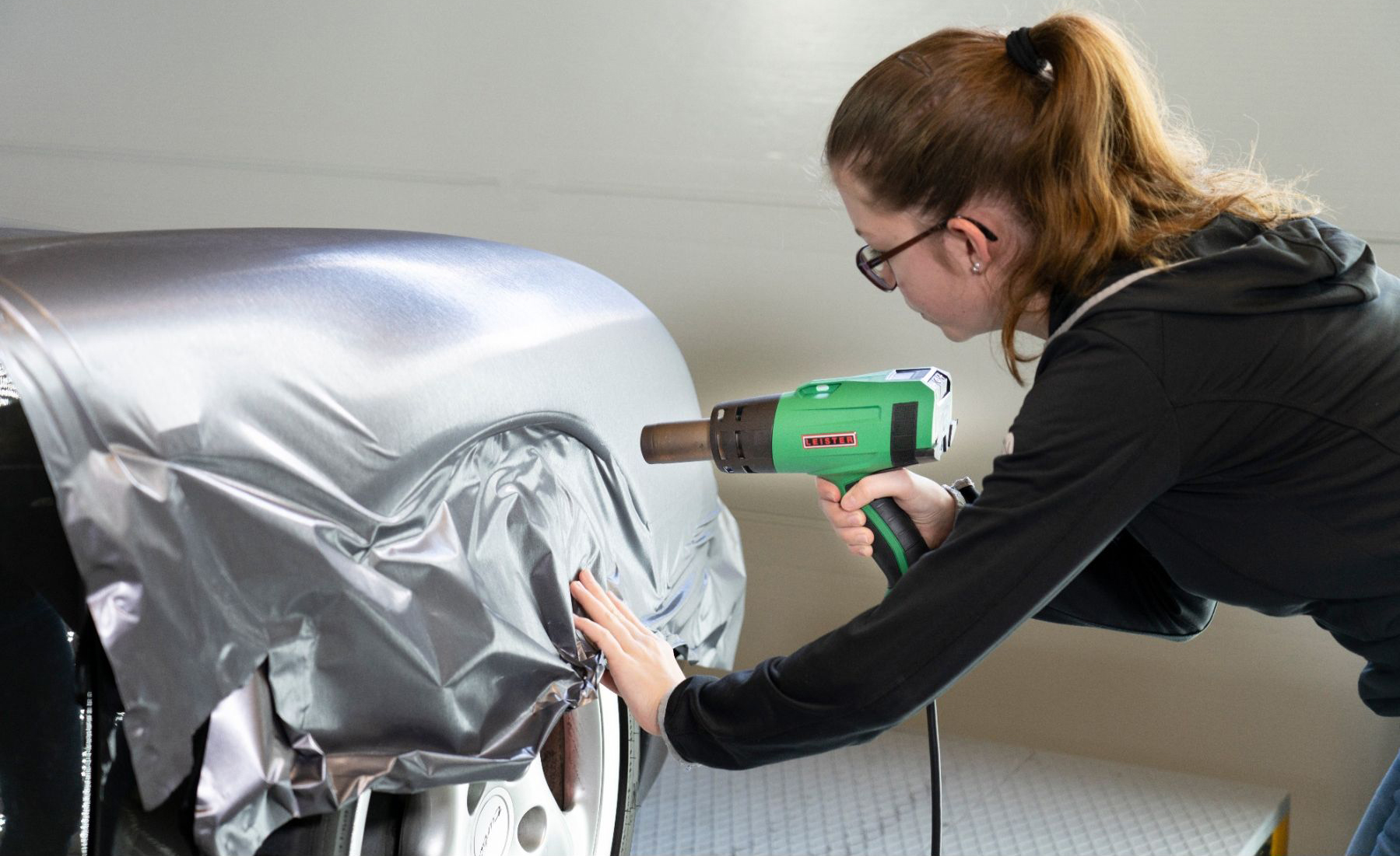 Aplicación profesional de vinilo mate en vehículo utilizando la pistola de calor Leister SOLANO AT para un acabado sin imperfecciones